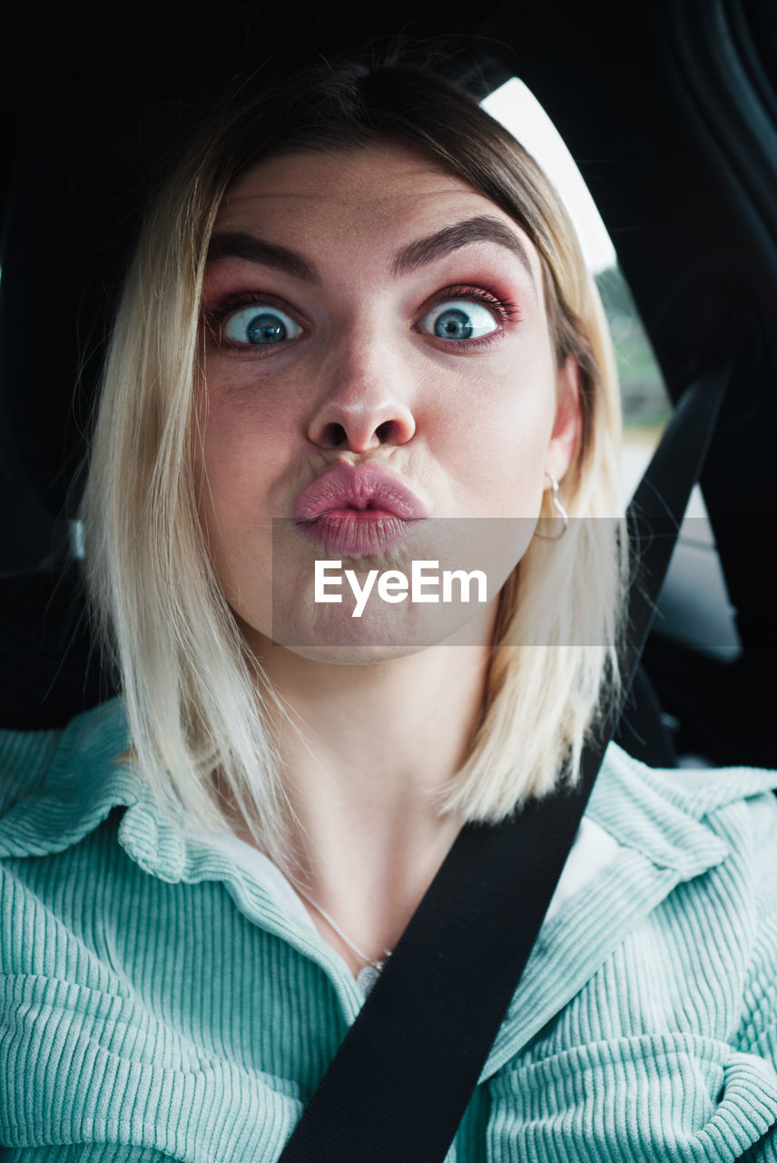 Close-up portrait of beautiful young woman making face while sitting in car