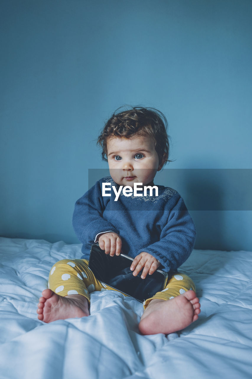 Cute girl sitting on bed at home