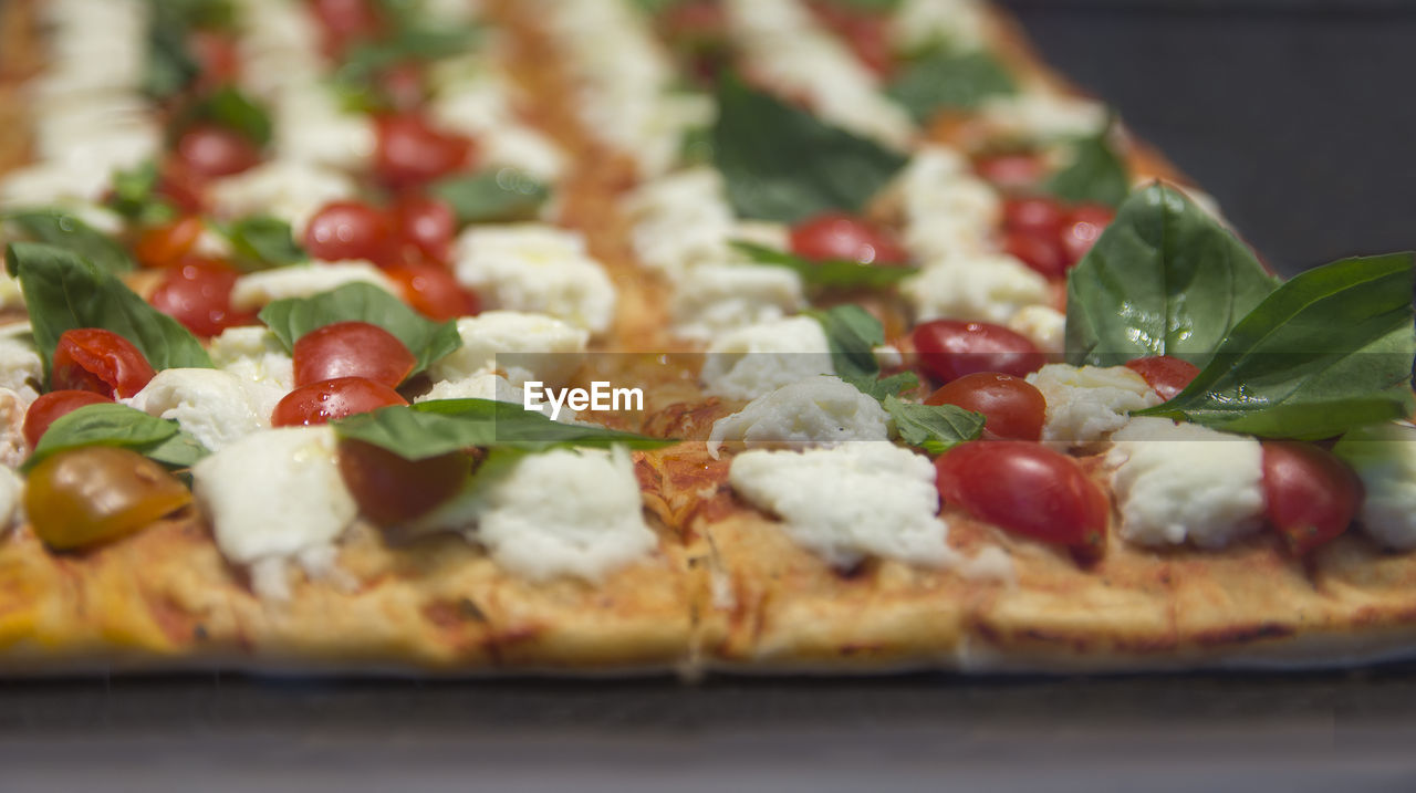 food, food and drink, pizza, vegetable, italian food, freshness, fruit, dish, dairy, herb, basil, cheese, tomato, cuisine, no people, healthy eating, fast food, mozzarella, leaf, baked, close-up, selective focus, indoors, plant part, produce, flatbread, olive, business, restaurant, savory food, green