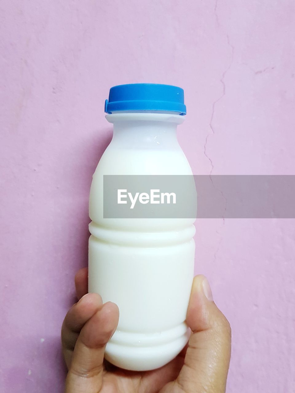 Fresh milk in the bottle with human hand