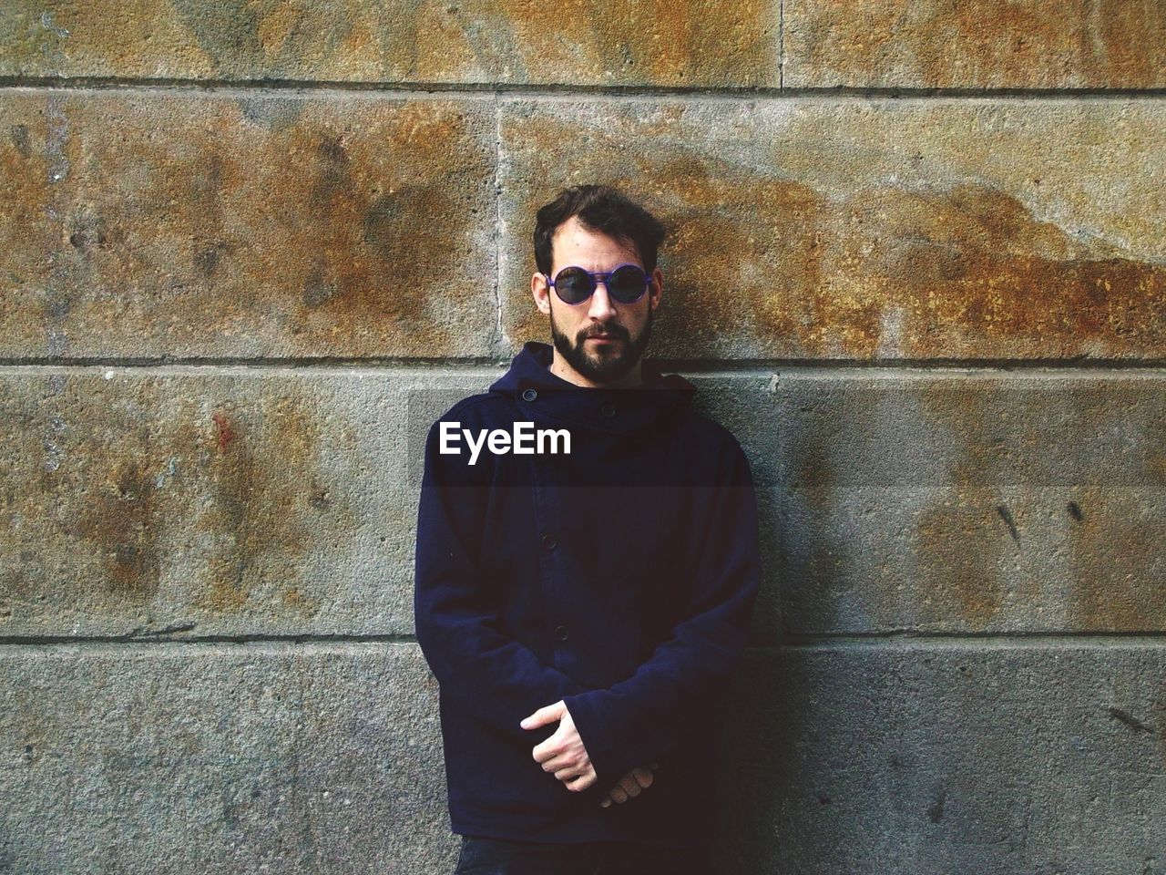 Portrait of mid adult man wearing sunglasses while standing against wall