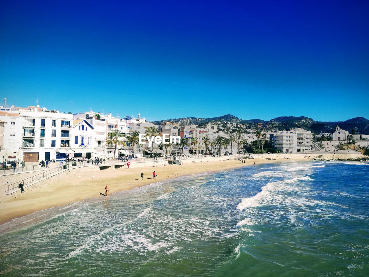 Buildings by sea against blue sky