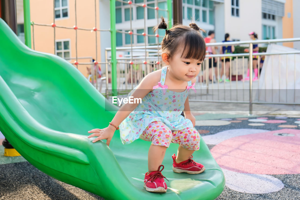 Full length of baby girl standing on slide at park