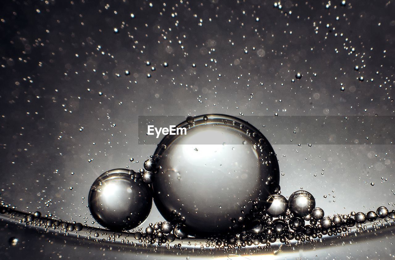 CLOSE-UP OF RAINDROPS ON GLASS WINDOW AGAINST BLACK BACKGROUND