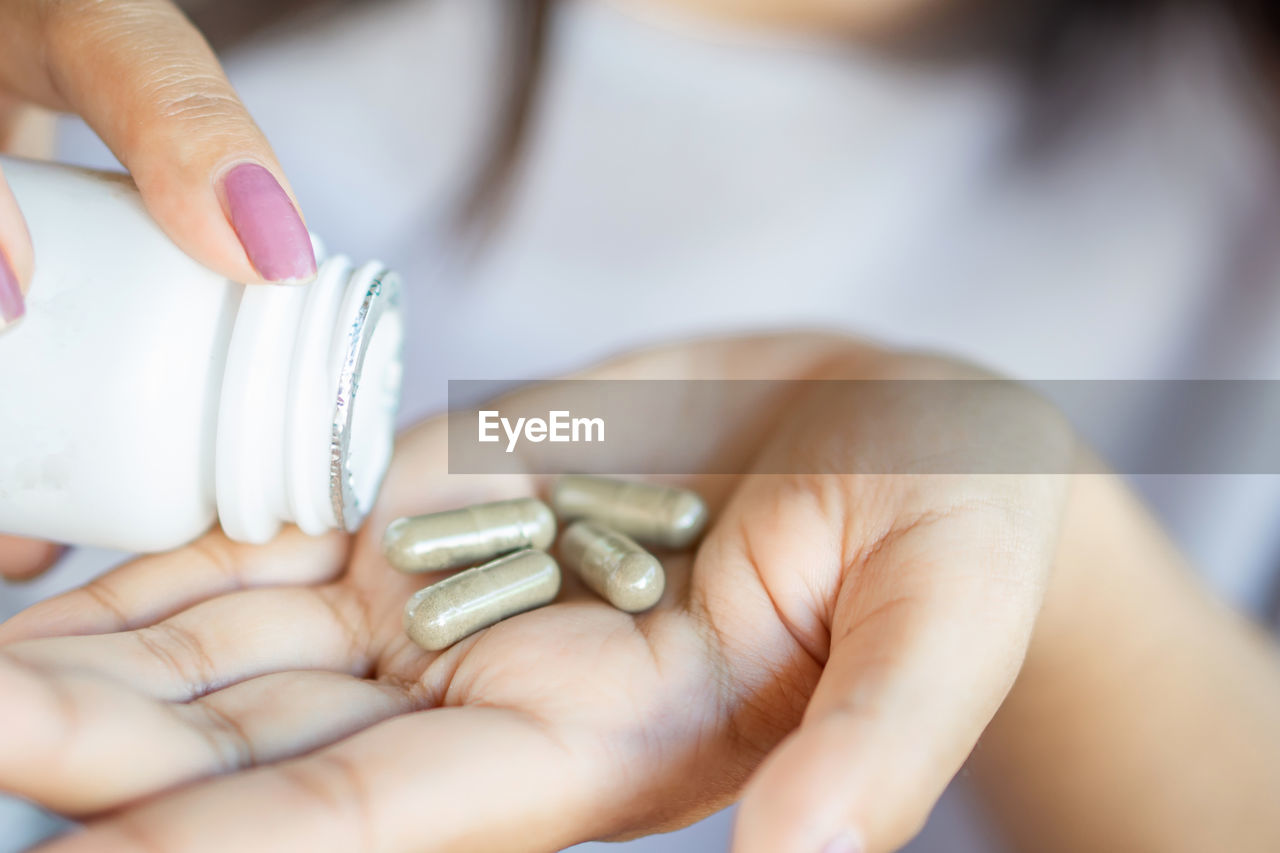 Closeup woman hand taking herb medicine tablets