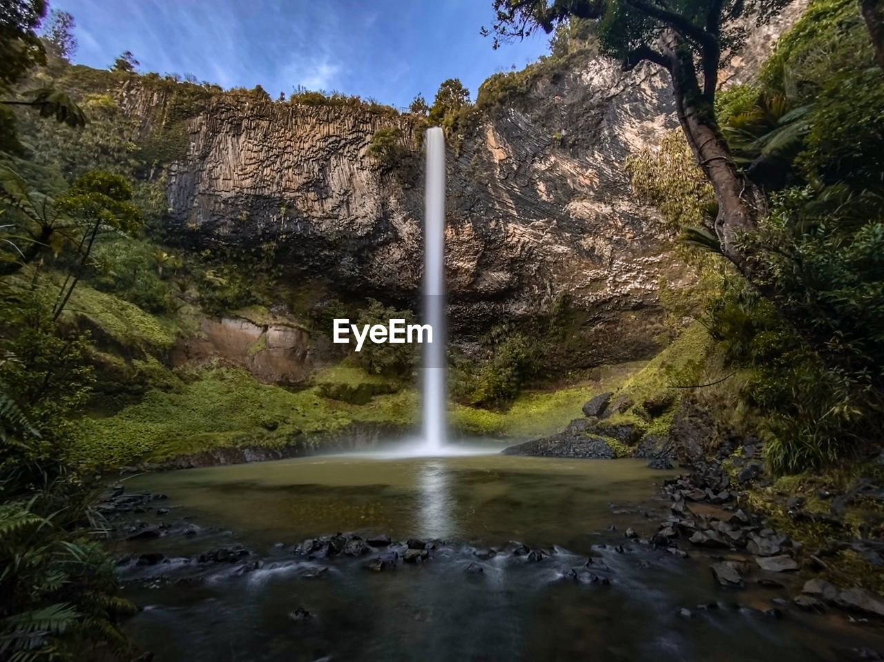 SCENIC VIEW OF WATERFALL IN FOREST AGAINST SKY