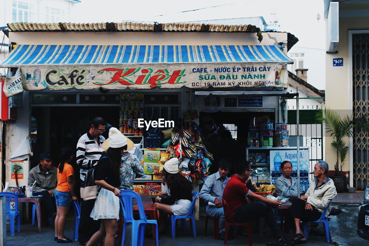 PEOPLE STANDING IN FRONT OF CAFE