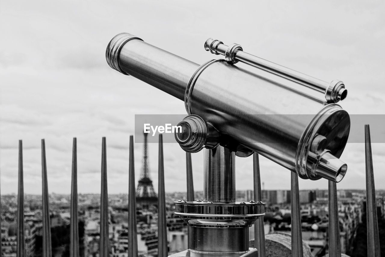 Close-up of hand-held telescope against eiffel tower in city
