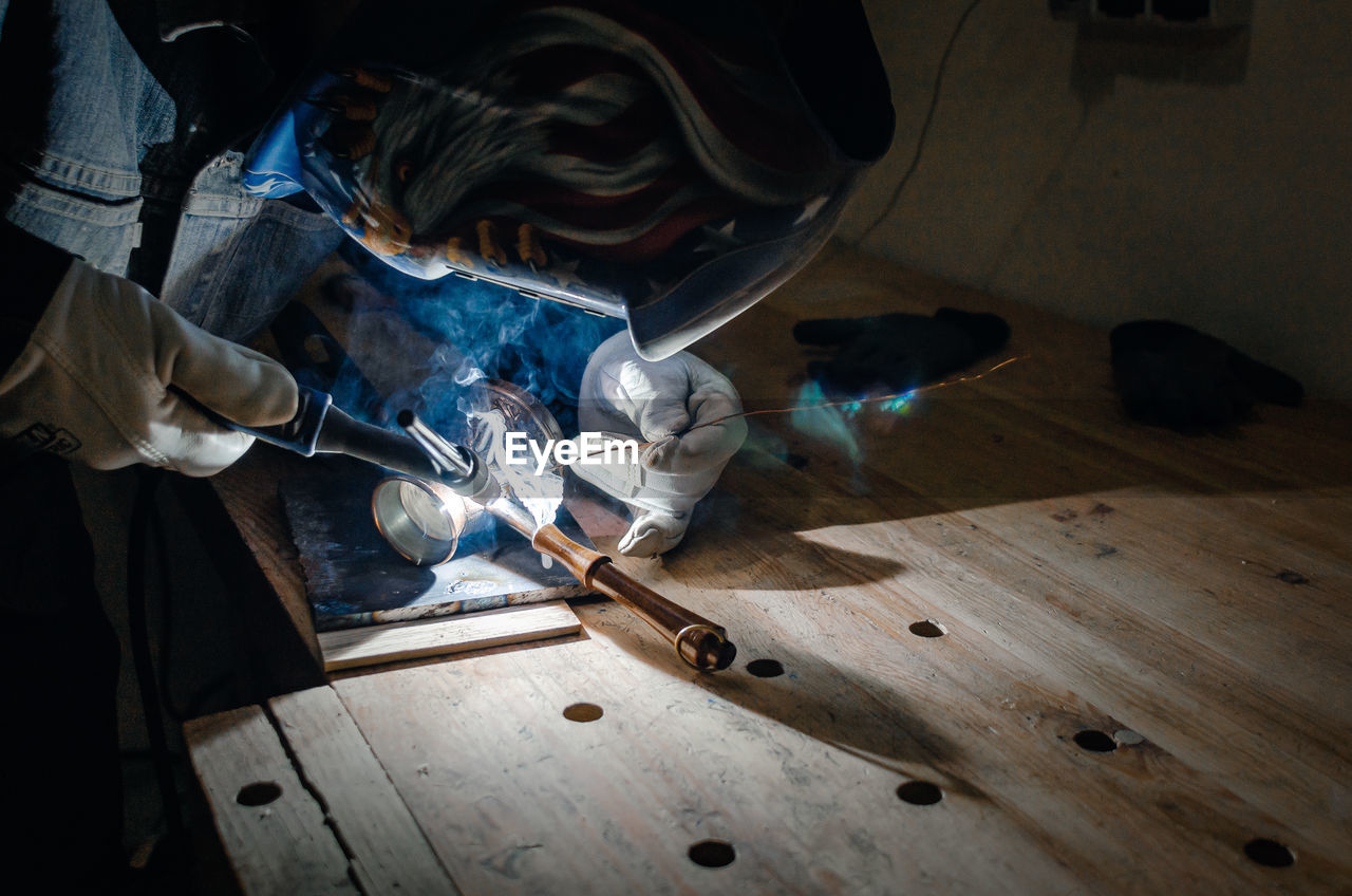 Man in protective mask. metal welding. coffee maker repair.