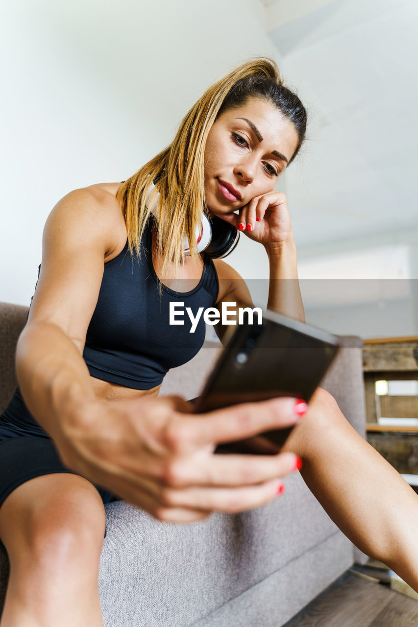 MIDSECTION OF WOMAN USING PHONE WHILE SITTING ON MOBILE SMART