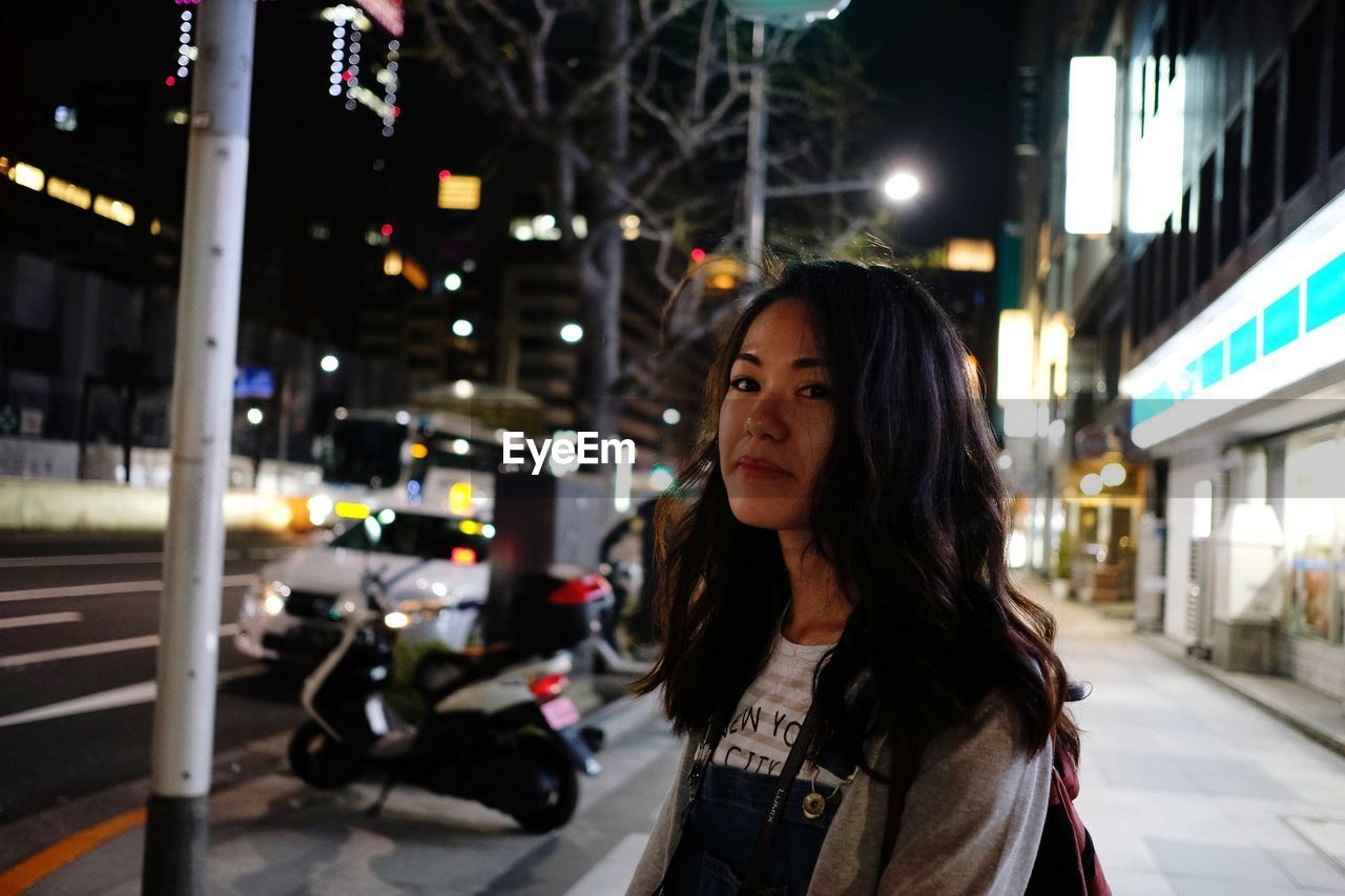 Woman standing in city at night