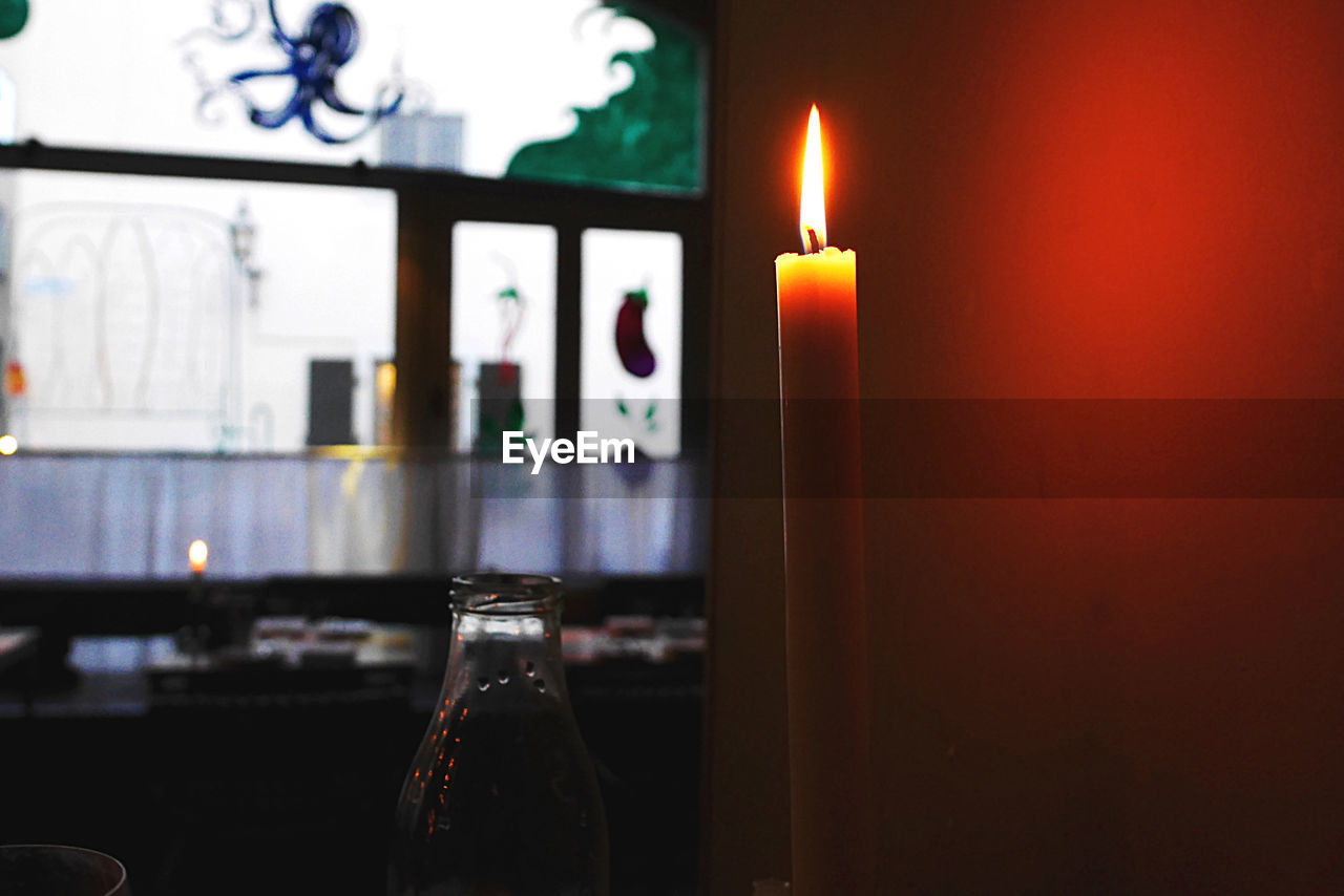 candle, fire, burning, flame, indoors, light, lighting, no people, illuminated, nature, table, food and drink, lighting equipment, bottle, heat, glass, domestic room, close-up, red, focus on foreground, interior design, container