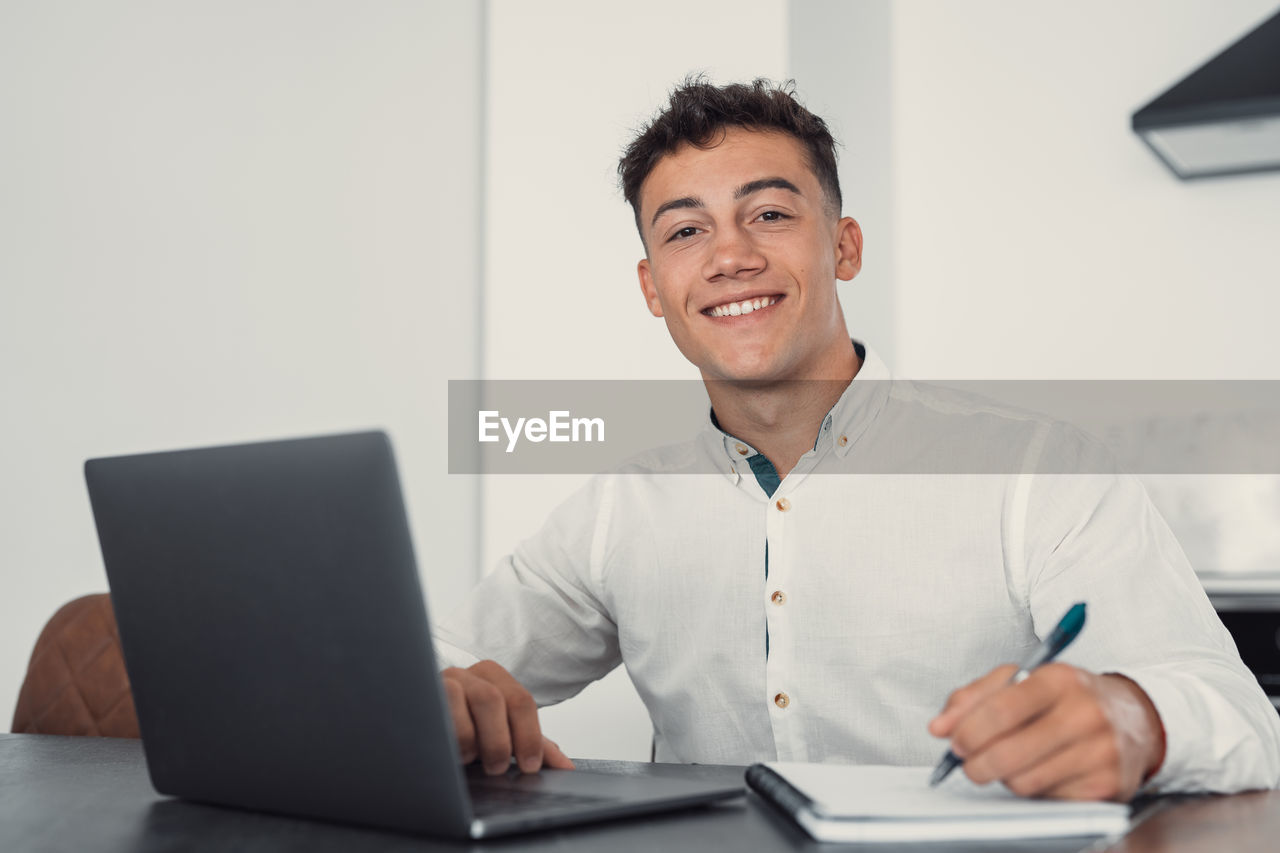 portrait of young woman using laptop while sitting on table