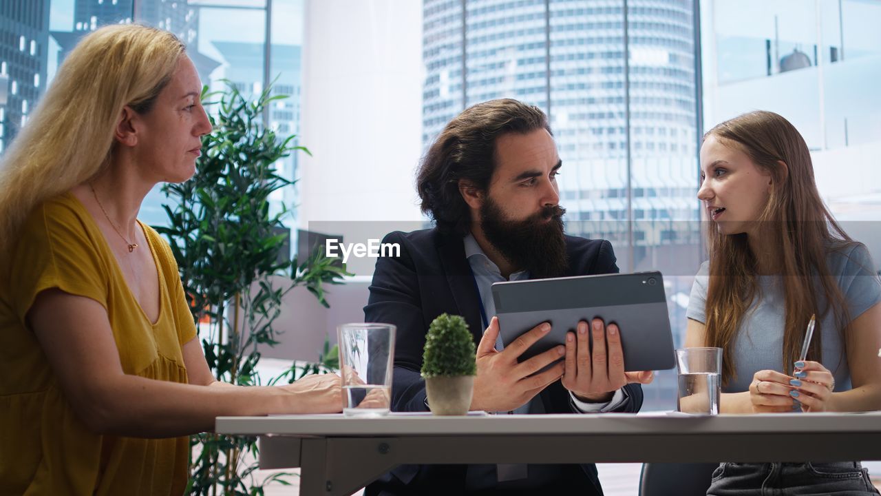 smiling friends using laptop while sitting at table