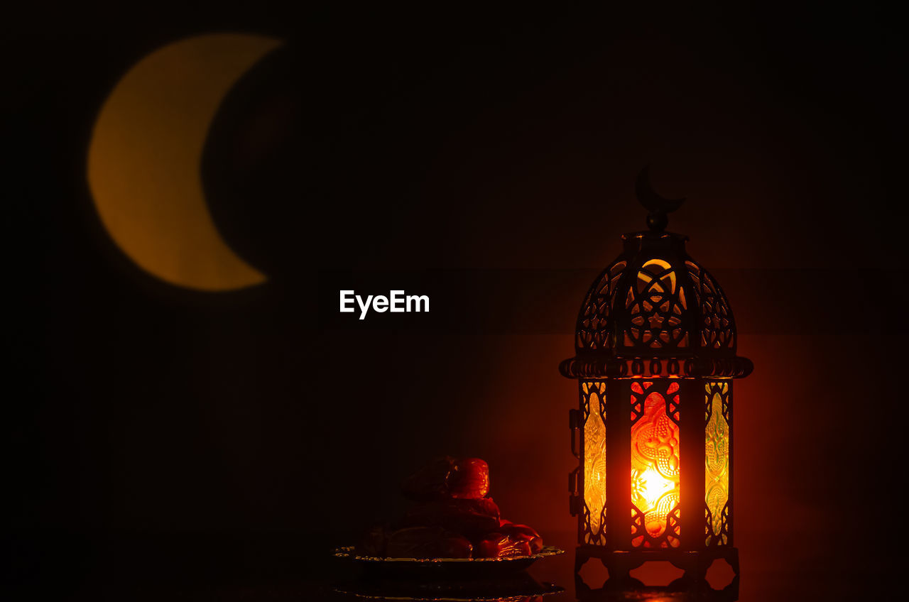 Lantern and small plate of dates fruit with moon shape from light  for holy month of ramadan kareem.