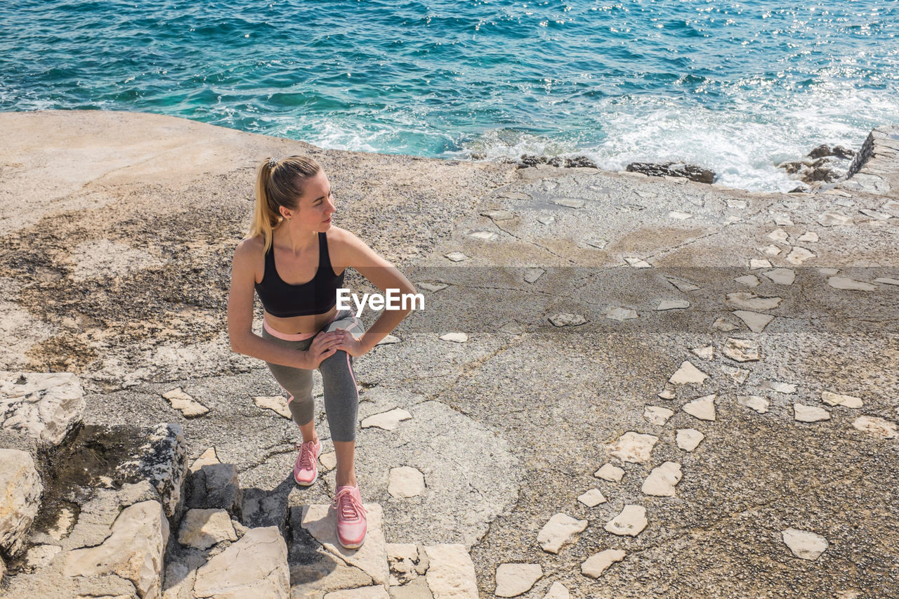 Woman running training on sea coastline under sunlight in sunny summer day. sport, run, health.