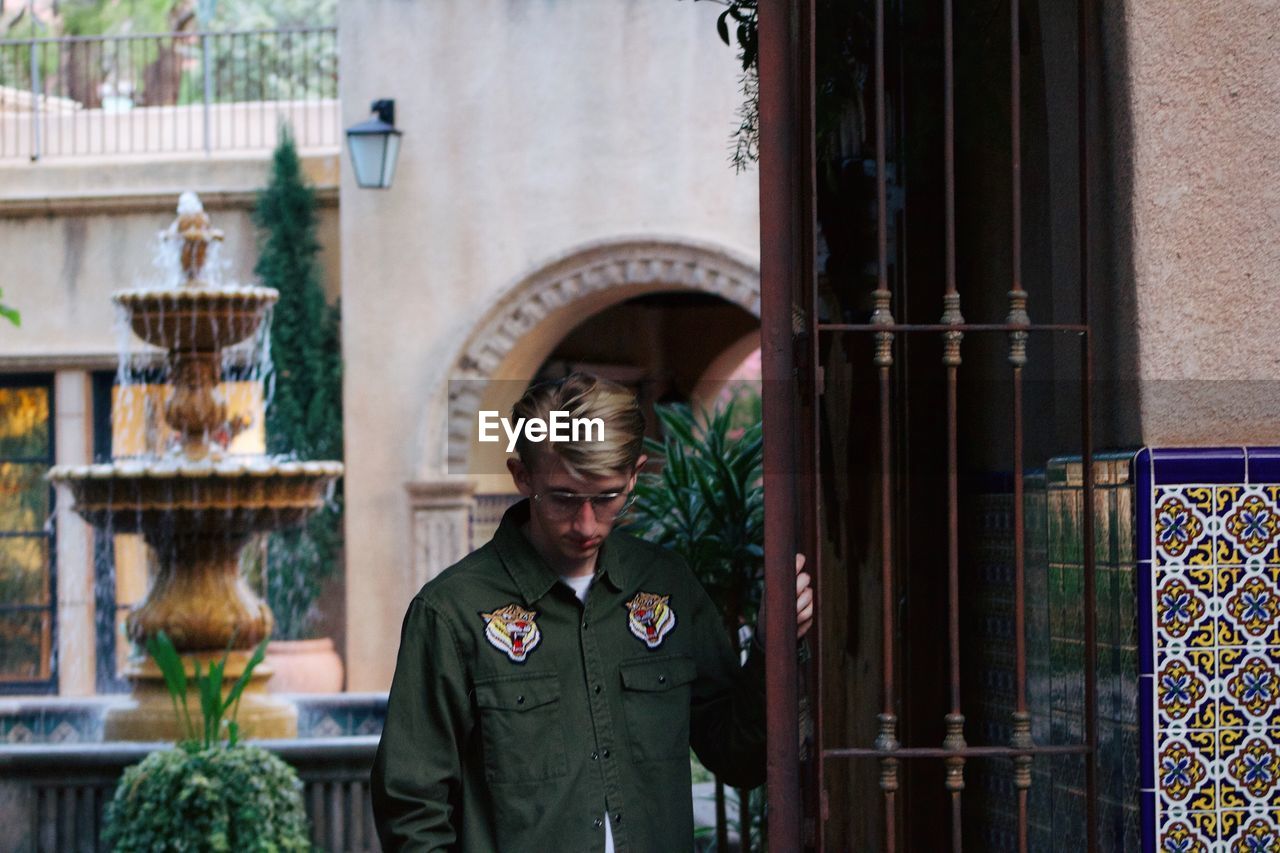 Man wearing sunglasses while standing metal gate