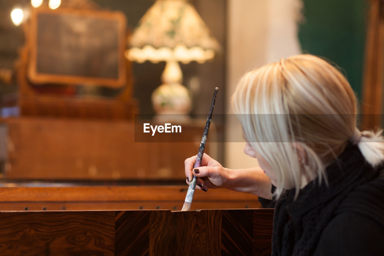 Woman painting furniture in store