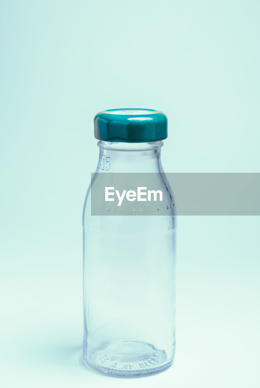 Close-up of empty glass bottle against blue background