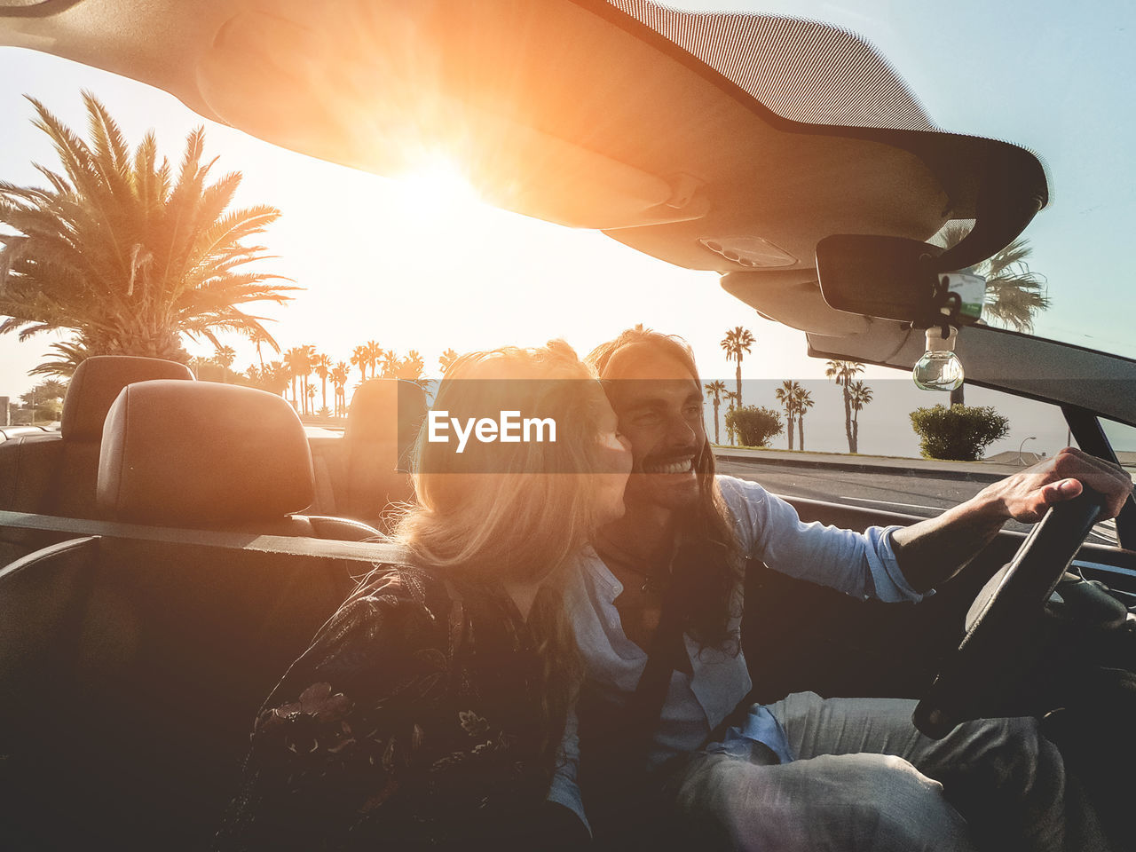 Couple sitting in car against sky