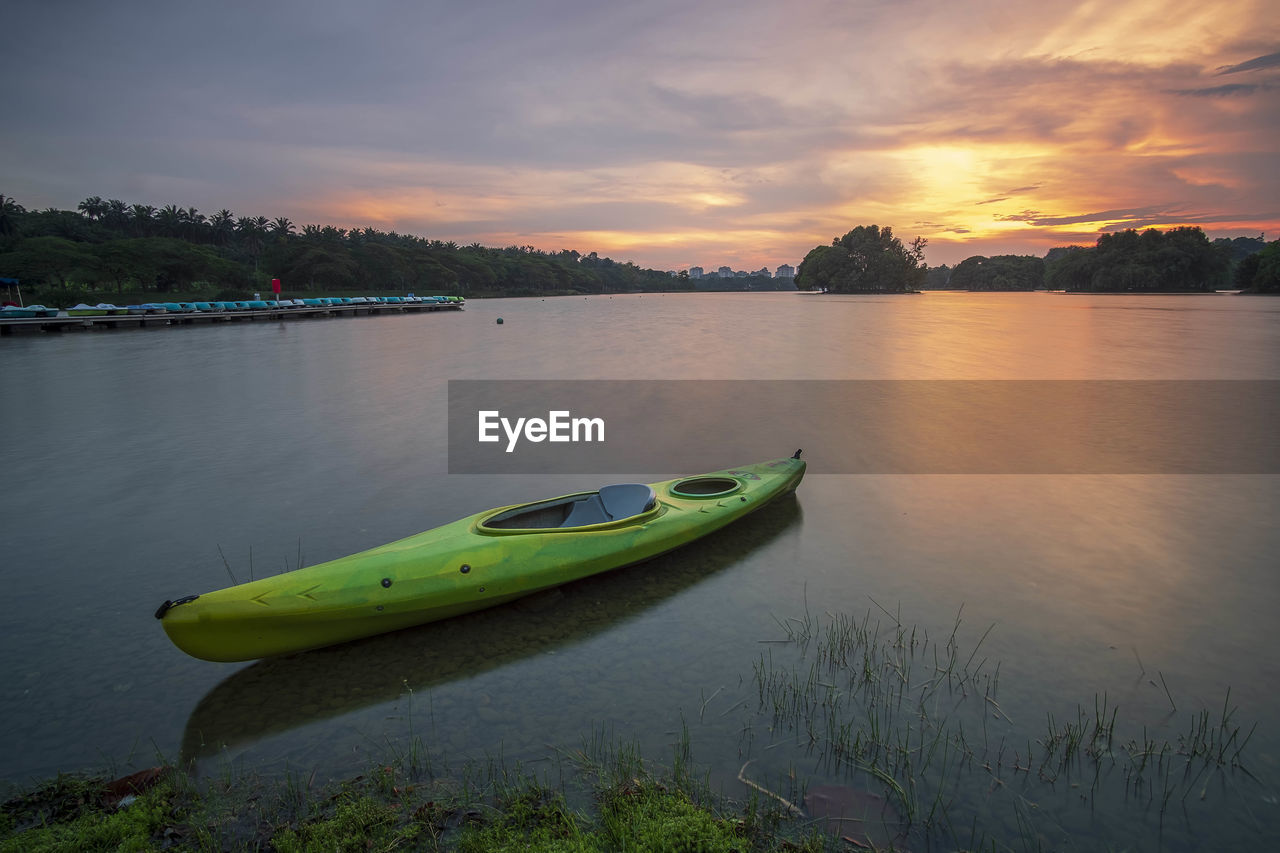 Kayak moored at lake against sky during sunset