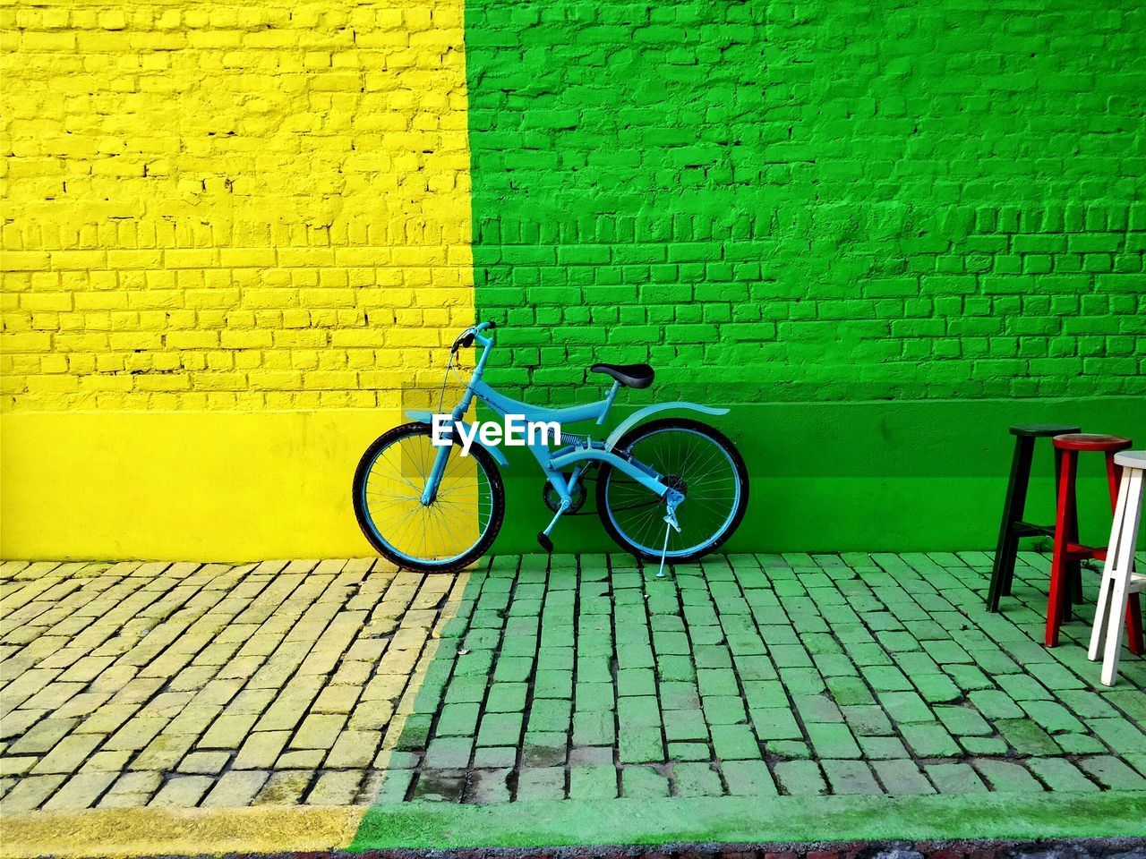 Bicycle parked on footpath against wall