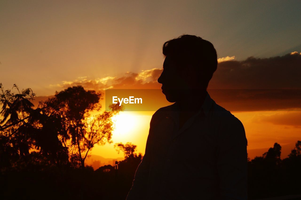 Silhouette man standing on field against cloudy sky during sunset