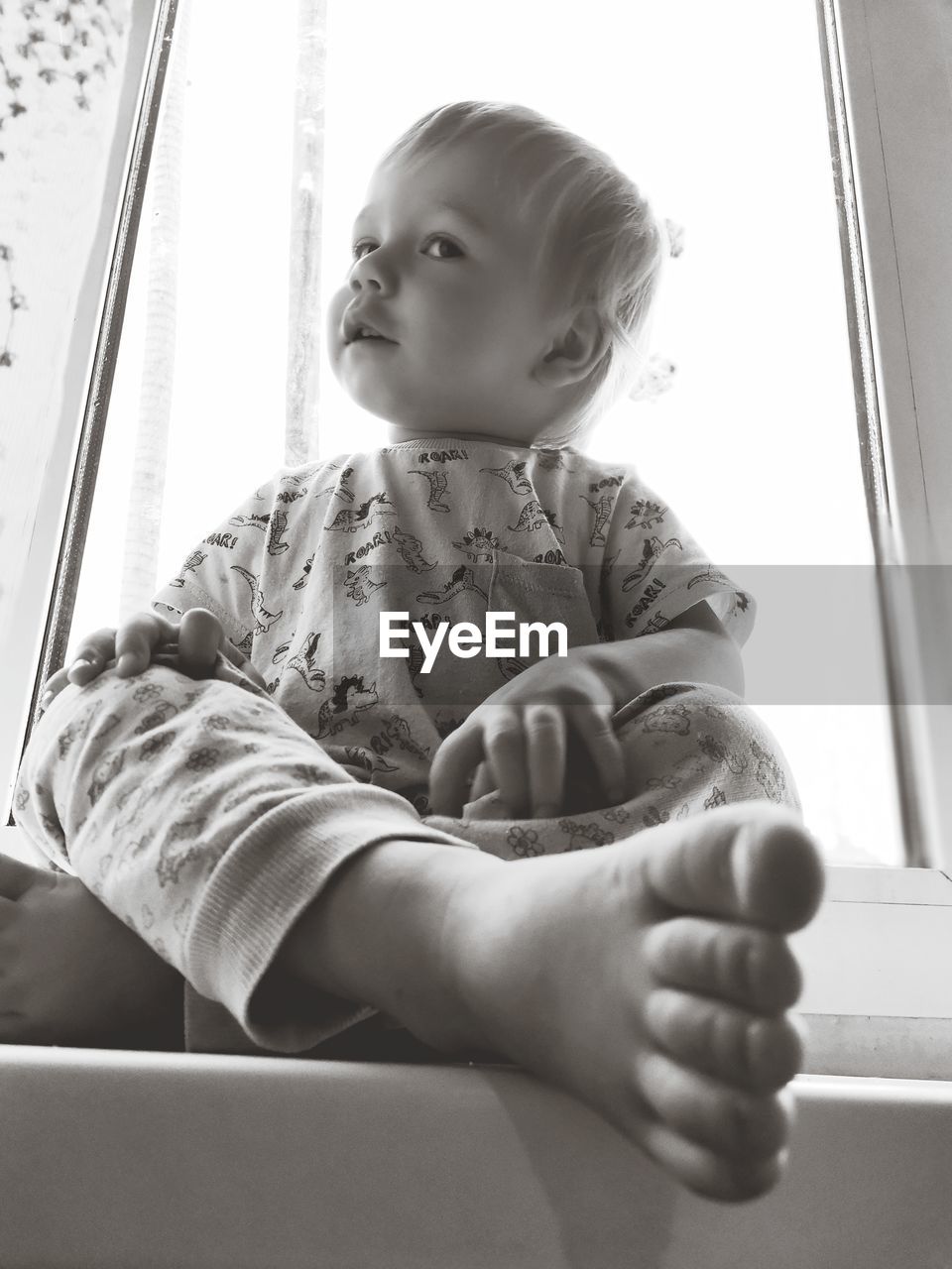 CUTE BABY BOY SITTING ON WINDOW AT HOME