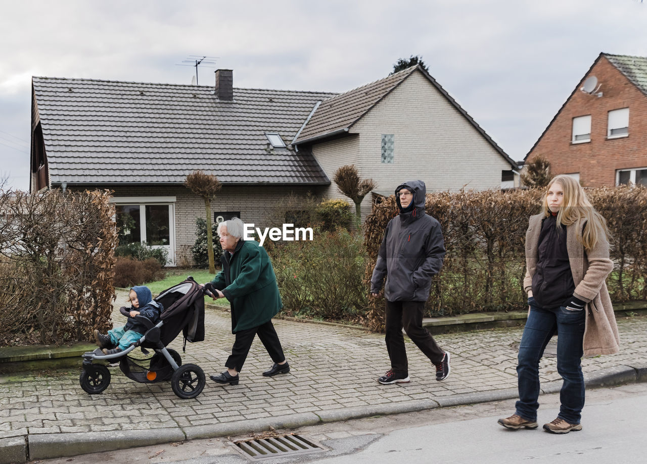 Group of people walking on sidewalk by building in city