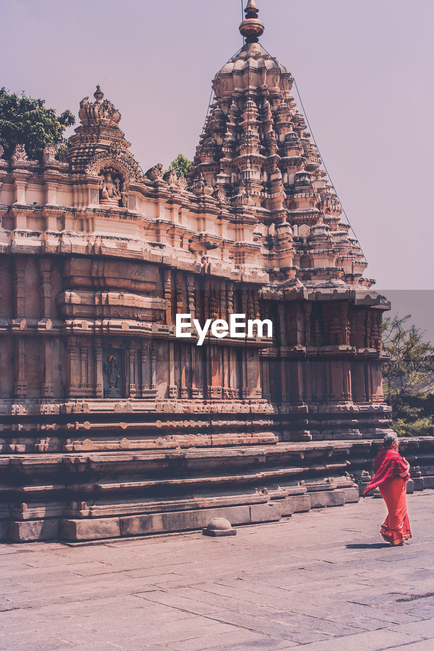 Rear view of people looking at temple against sky