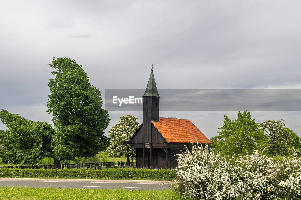 architecture, built structure, plant, building exterior, building, cloud, sky, rural area, place of worship, tree, religion, nature, landscape, belief, environment, house, spirituality, no people, grass, green, travel destinations, rural scene, history, land, spire, beauty in nature, the past, hill, tower, outdoors, field, overcast, residential district, day, scenics - nature, tourism, travel, steeple, non-urban scene, roof, growth, flower, tranquility