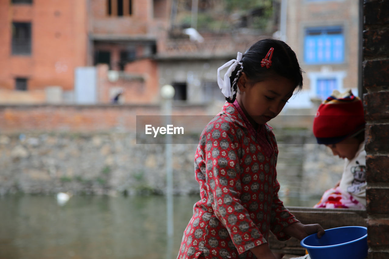 YOUNG WOMAN STANDING IN FRONT OF WATER