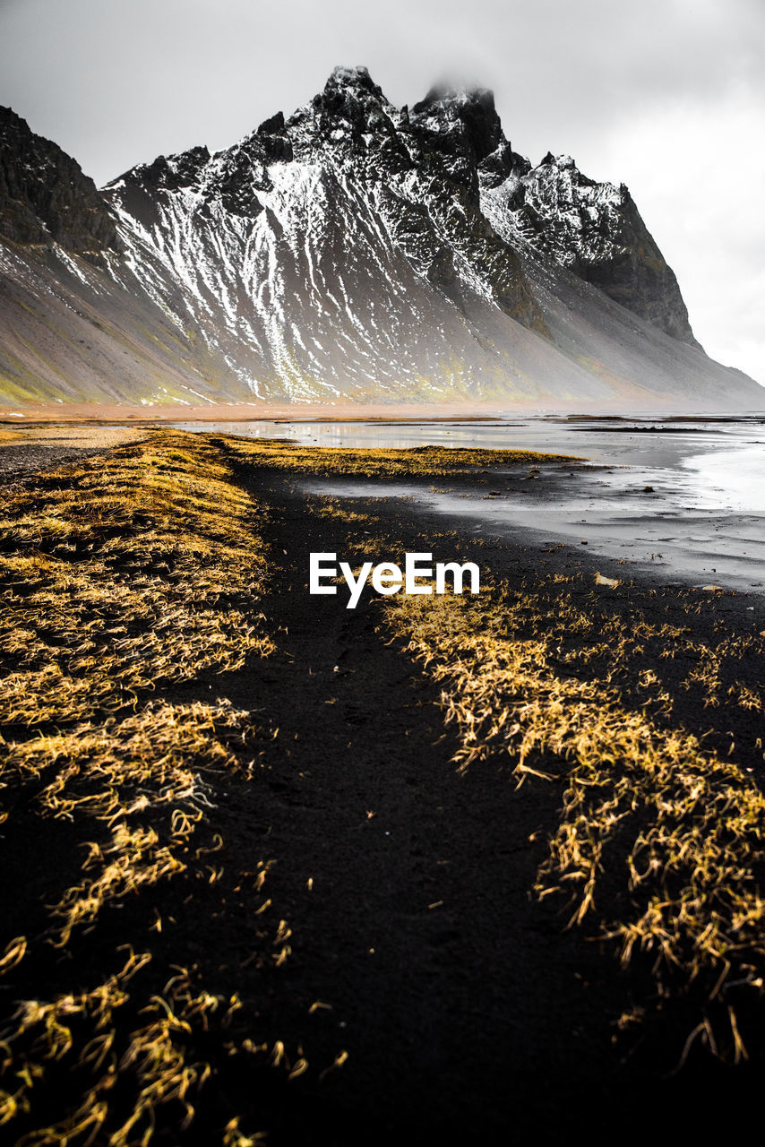 Scenic view of snowcapped mountains by sea against sky