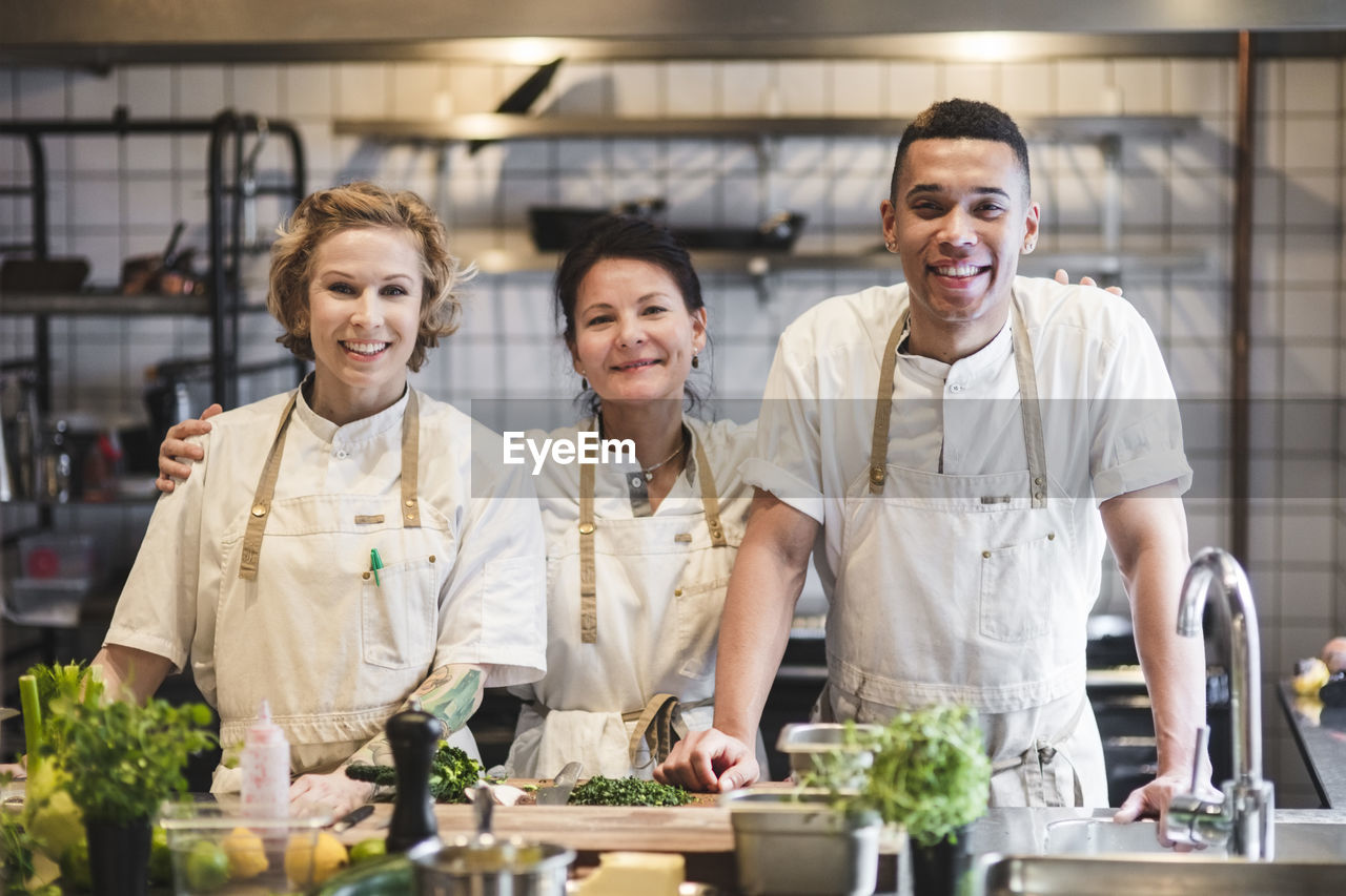 Portrait of smiling confident chefs standing at kitchen in restaurant