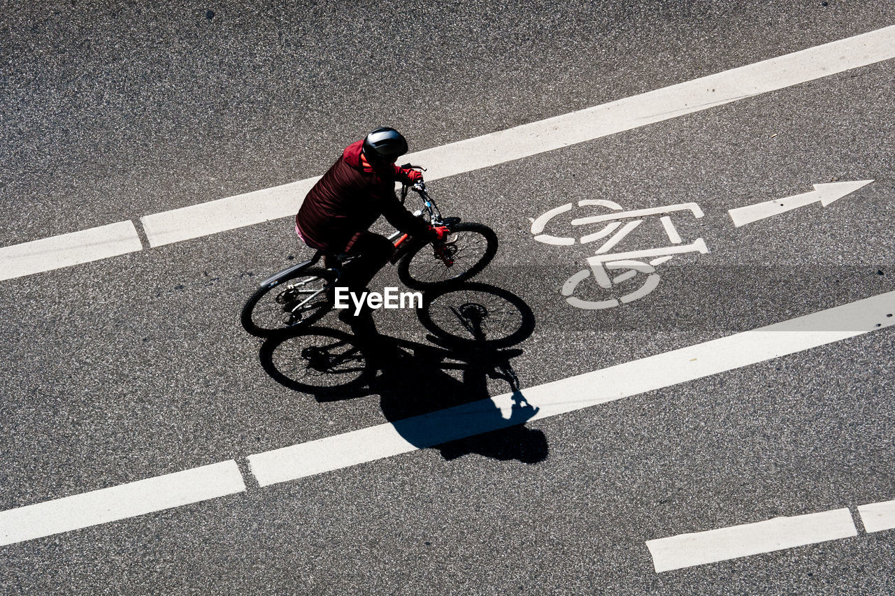 High angle view of man cycling on bicycle lane during sunny day