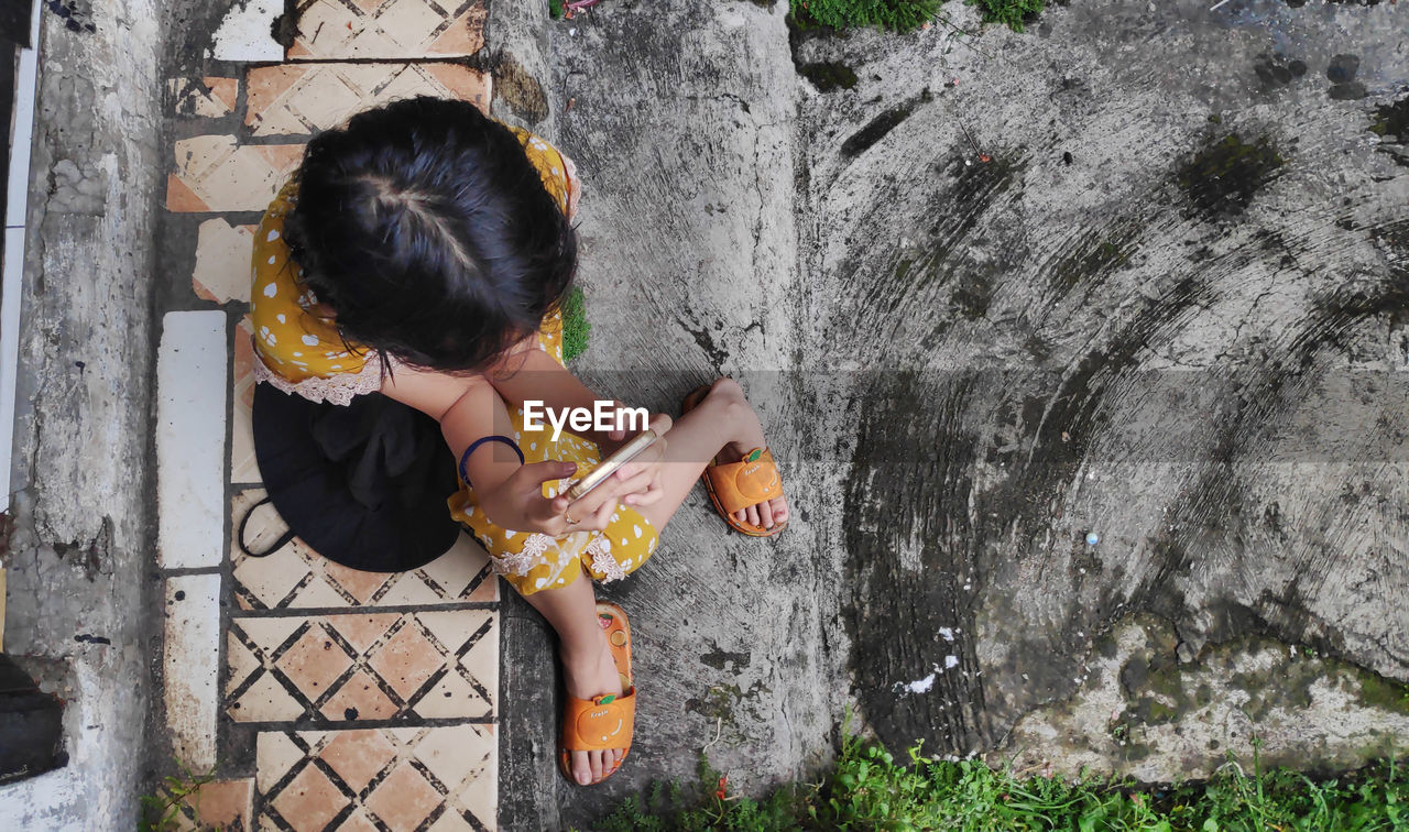 Cute little girl sitting in the back yard holding a cellphone