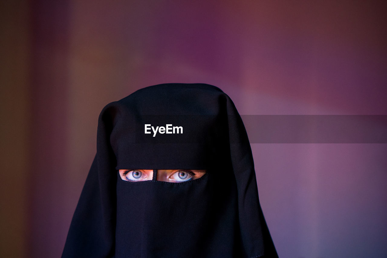 Portrait of woman wearing burka against wall