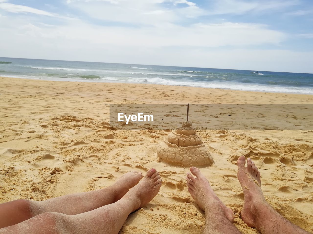 Low section of people at beach against sky