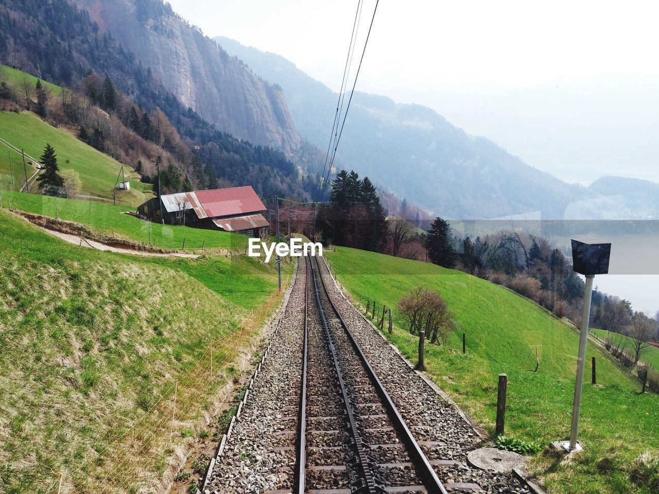 RAILROAD TRACK AMIDST GREEN LANDSCAPE AGAINST SKY