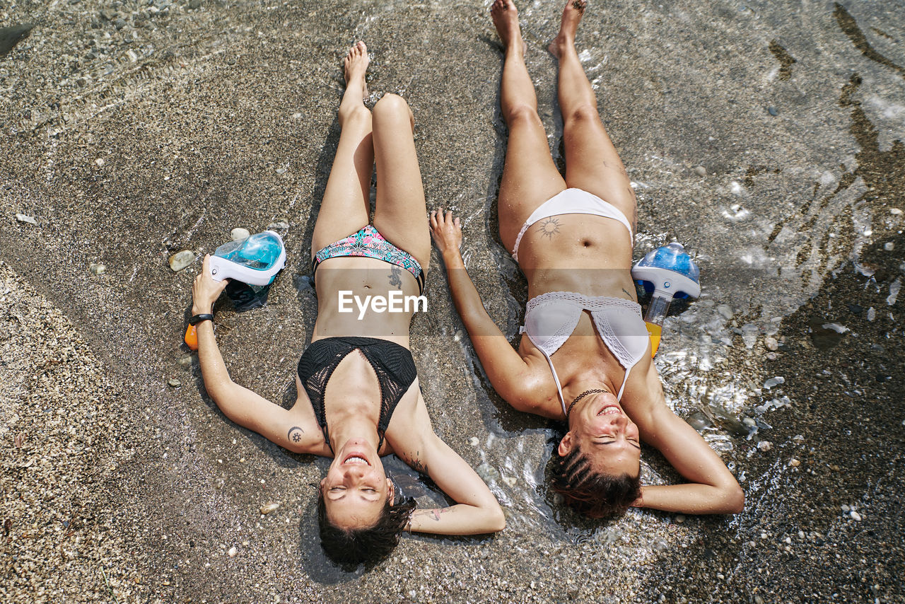 Two girls lying on the seashore sunbathing. holiday concept and lifestyle.