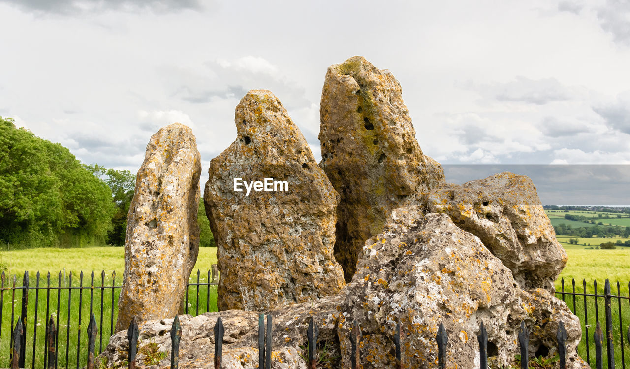 Close-up of neolithic rocks on field against sky