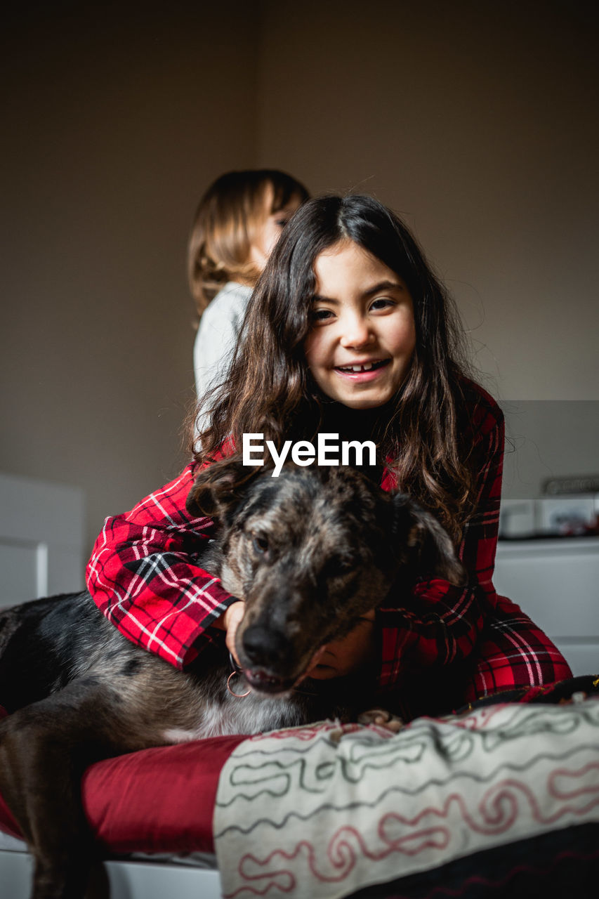 Smiling girl in red pajama holds her grey dog