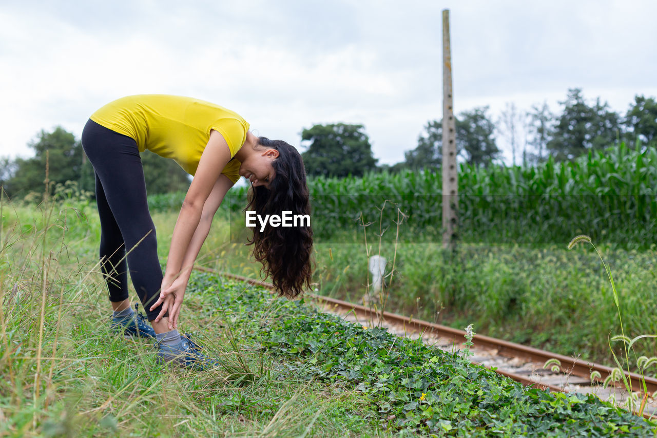 Active young woman doing stretching exercise in countryside