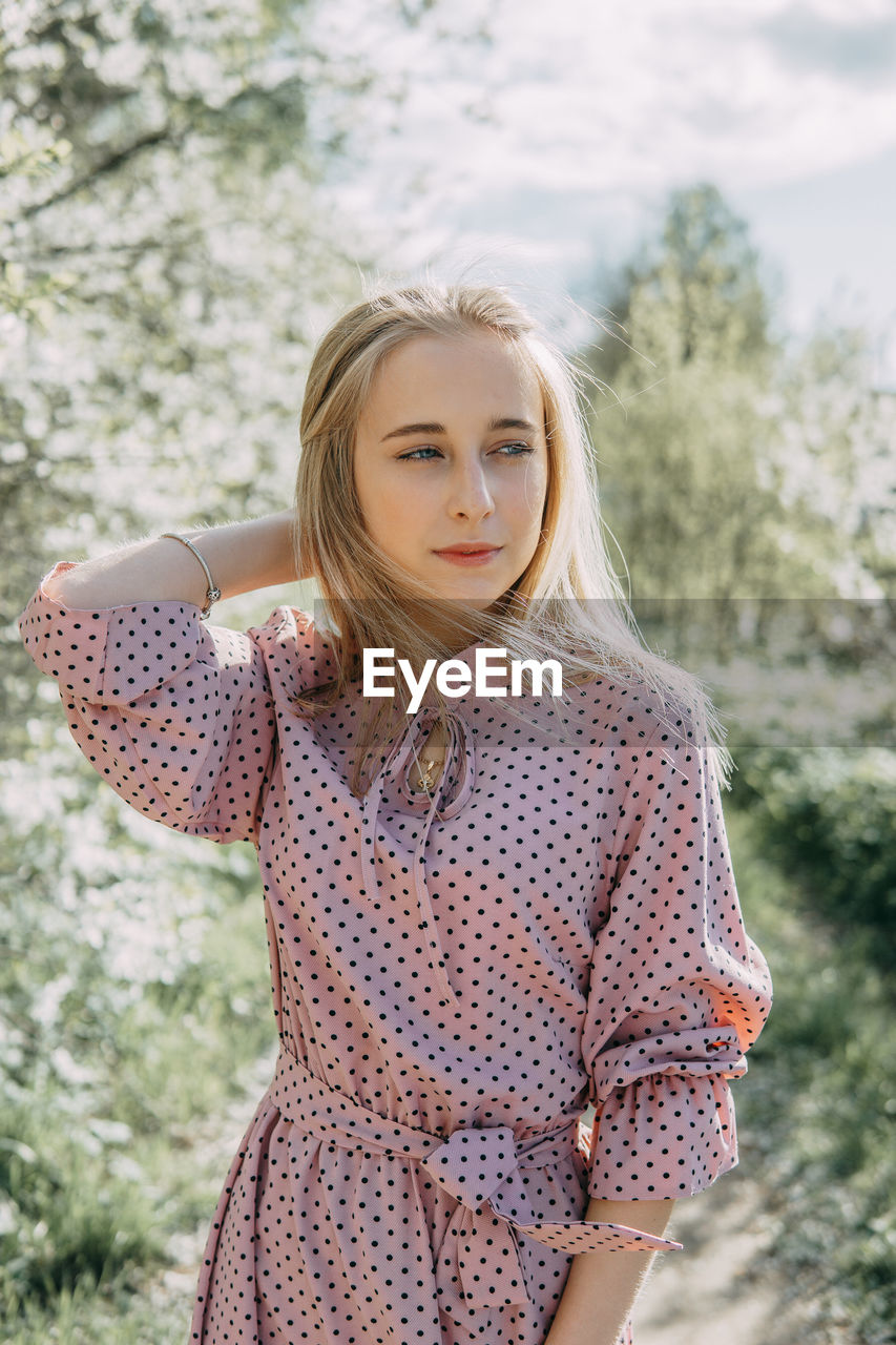 Blonde girl on a spring walk in the garden with cherry blossoms. female portrait, close-up. 