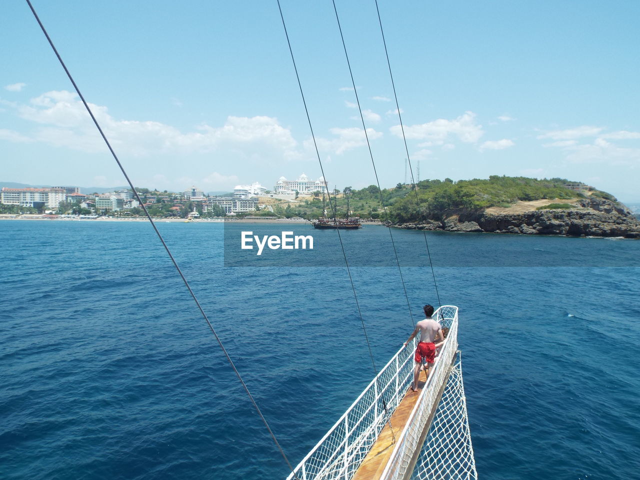 High angle view of shirtless man standing on boat over mediterranean sea