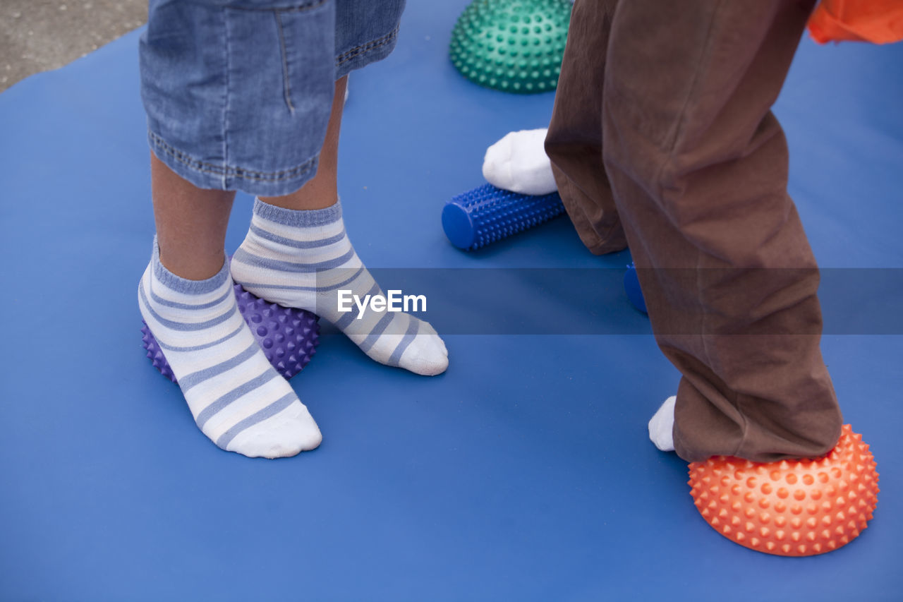 Low section of children wearing socks standing on spiked balls while exercising in gym