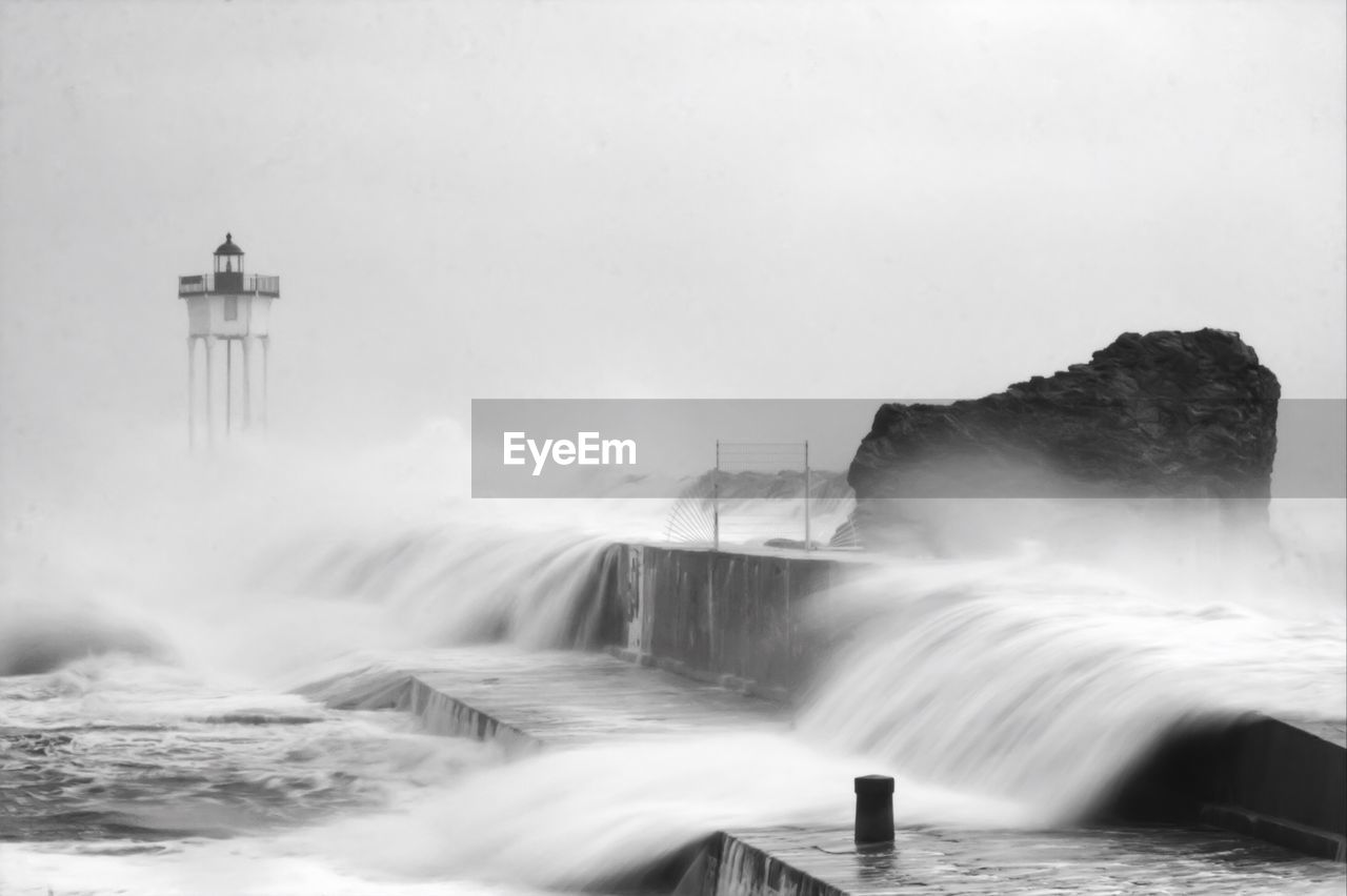 Waves crashing on rocks near lighthouse