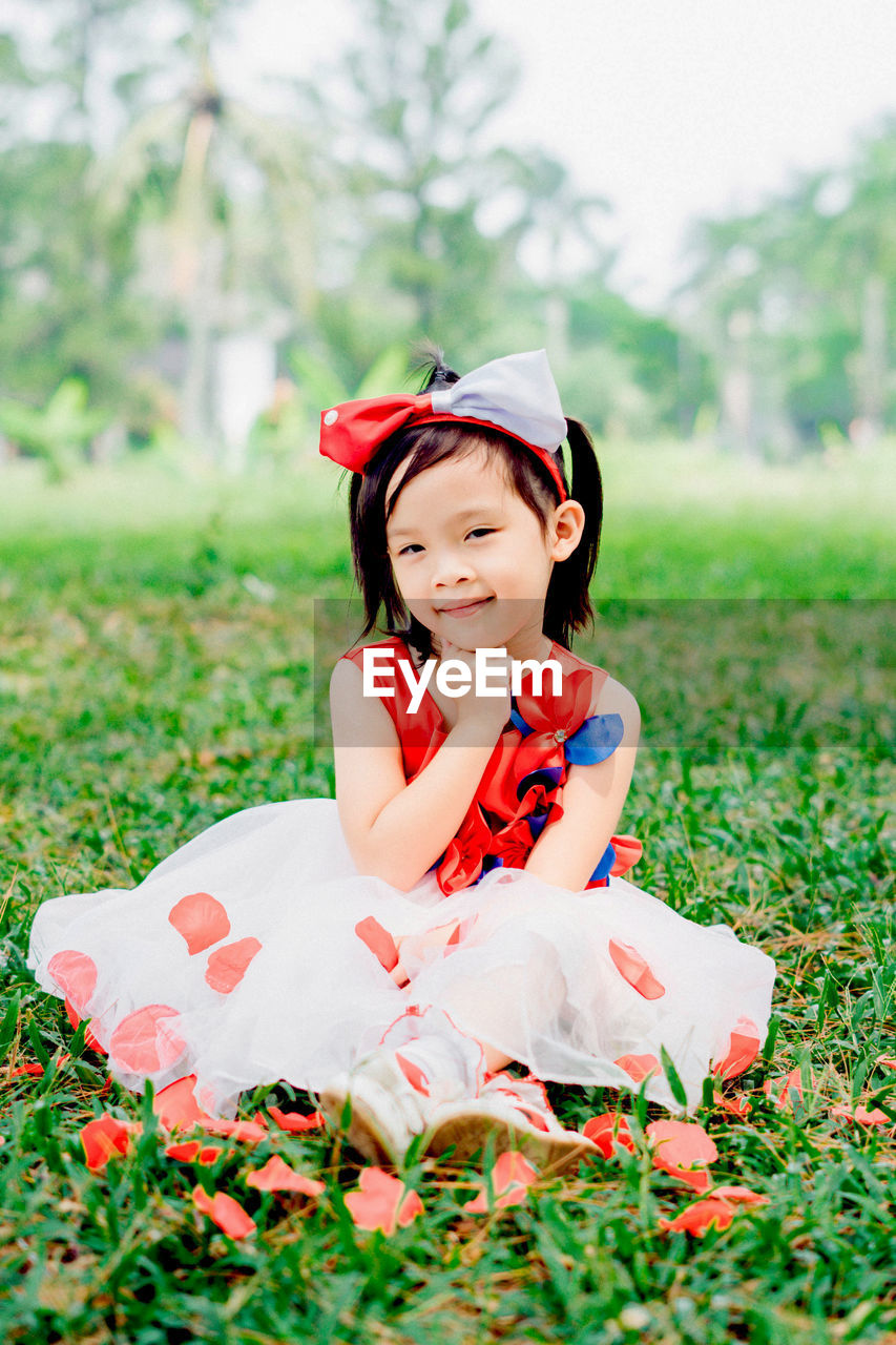 PORTRAIT OF A SMILING GIRL SITTING ON LAND