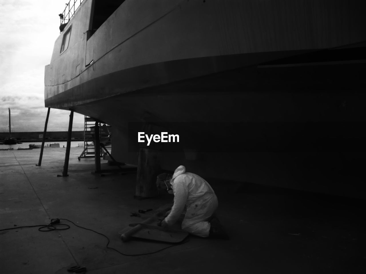 Full length of worker repairing boat part at port