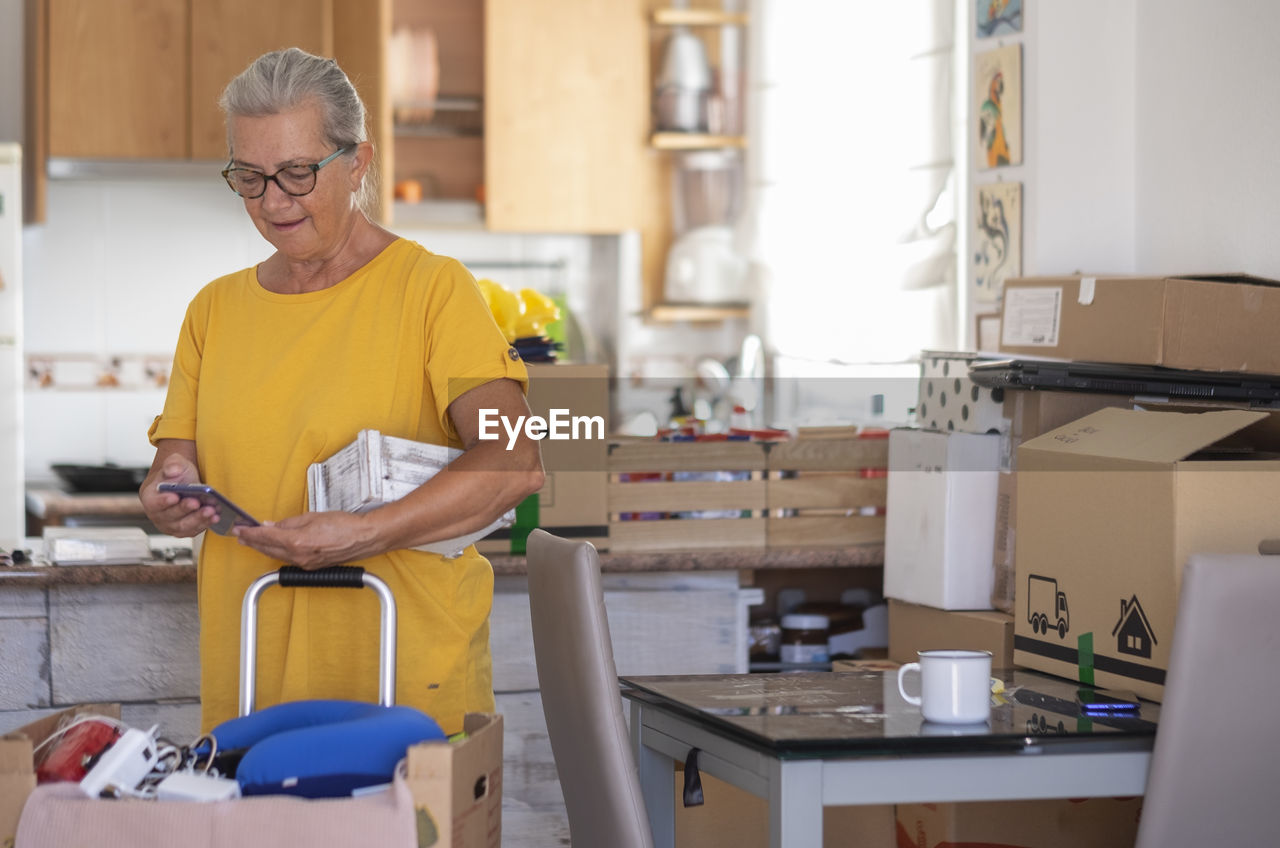 Smiling woman using phone standing at home